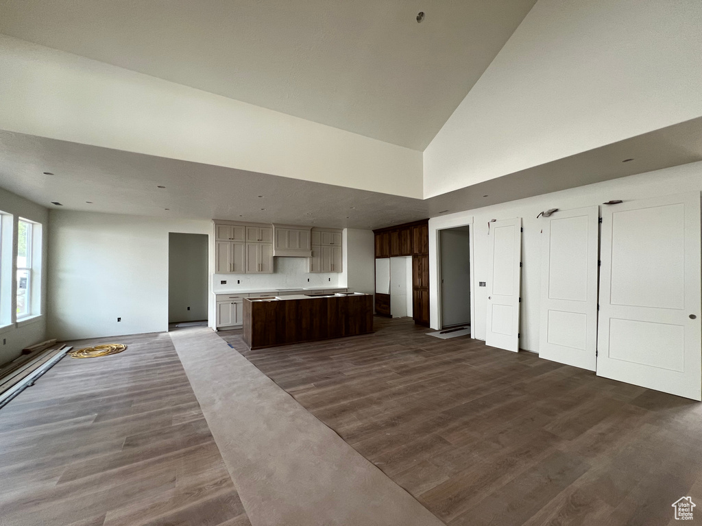 Kitchen with dark wood-style flooring, open floor plan, high vaulted ceiling, a kitchen island, and light countertops