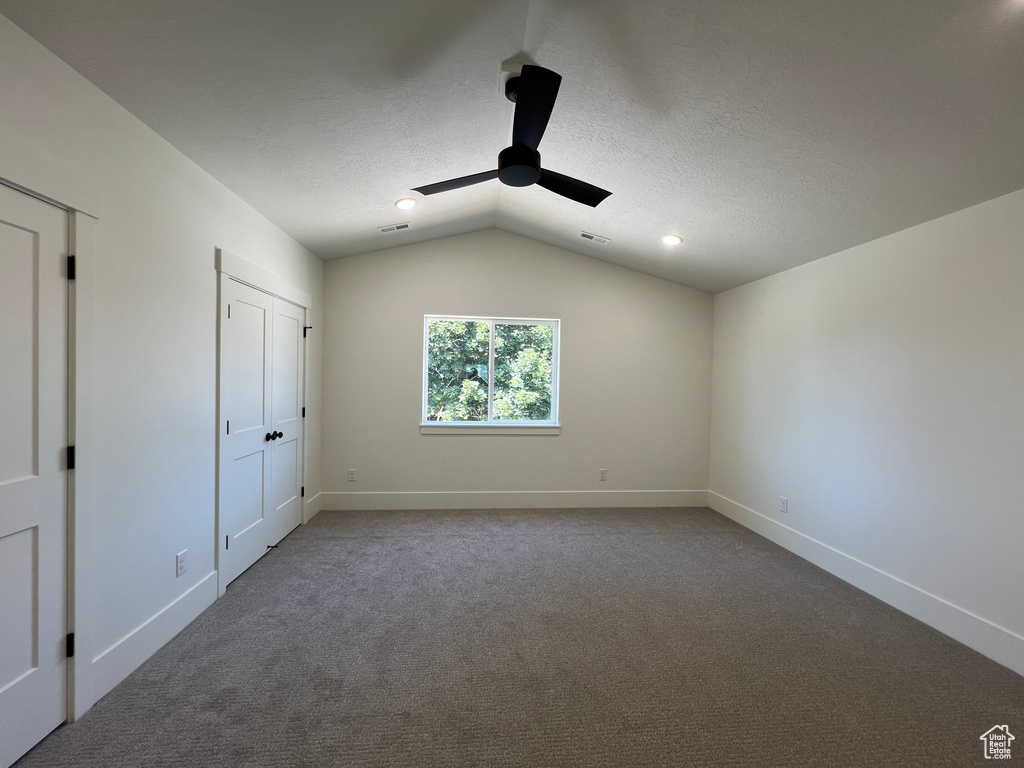 Unfurnished bedroom with vaulted ceiling, carpet floors, a ceiling fan, and a textured ceiling
