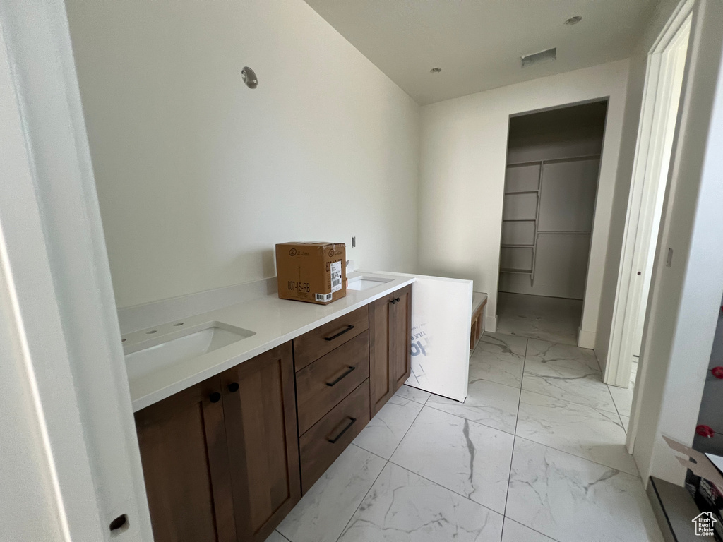 Laundry room with a sink, marble finish floor, and visible vents