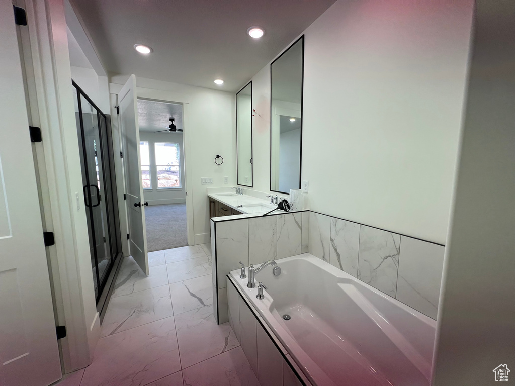 Bathroom featuring marble finish floors, a bath, double vanity, a stall shower, and recessed lighting
