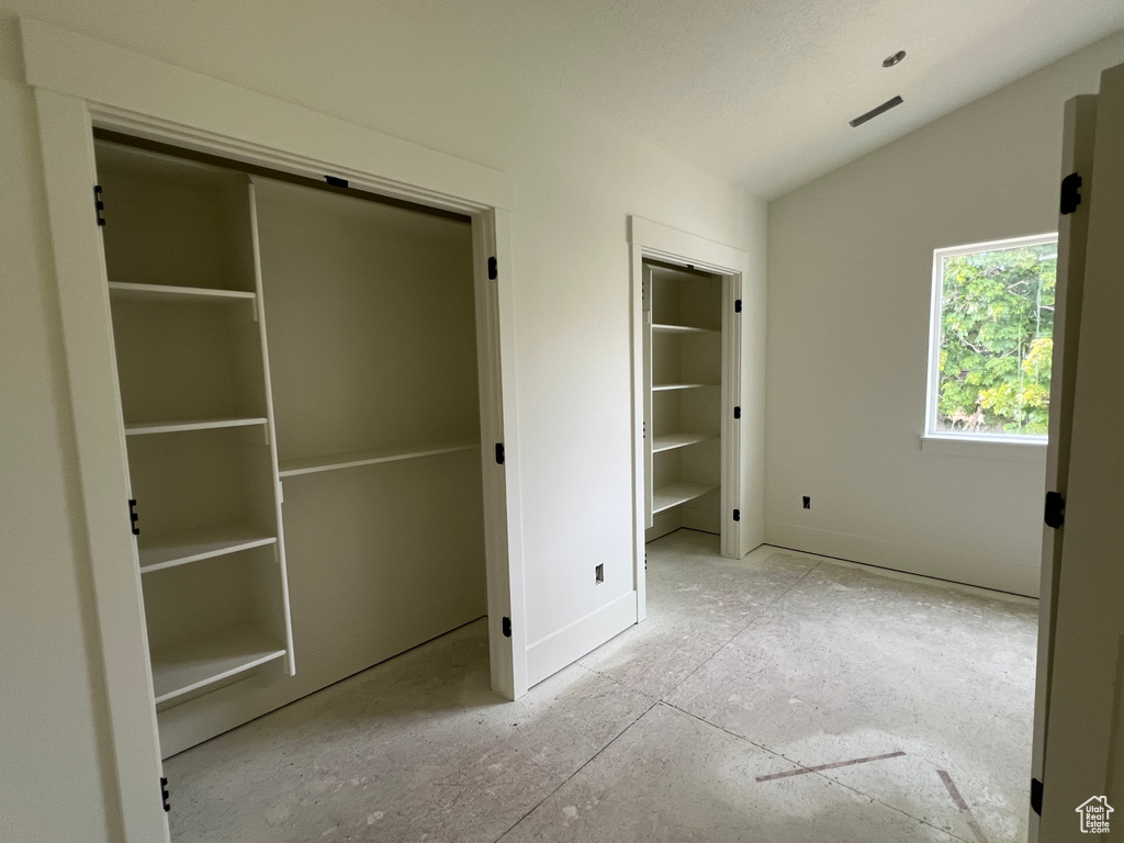 Unfurnished bedroom with vaulted ceiling and baseboards