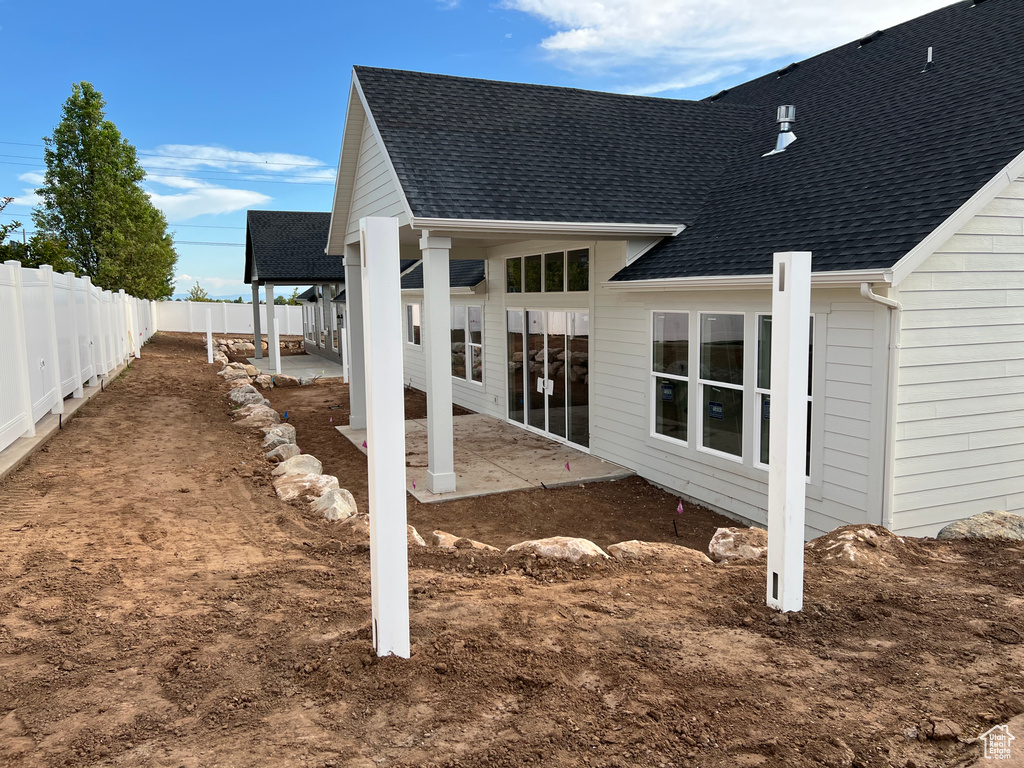 Rear view of house featuring a patio area, roof with shingles, and a fenced backyard