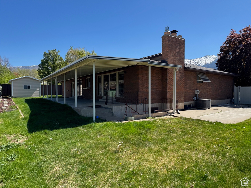 Back of property with brick siding, a mountain view, a yard, a patio, and a chimney