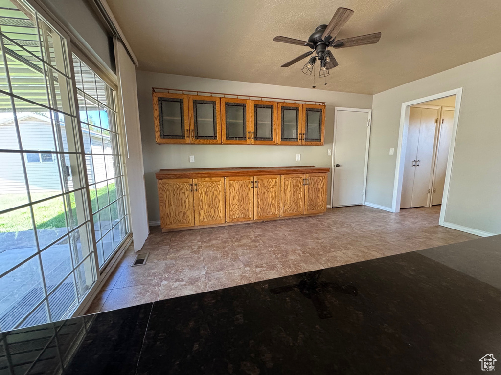 Kitchen with baseboards, glass insert cabinets, visible vents, and brown cabinets