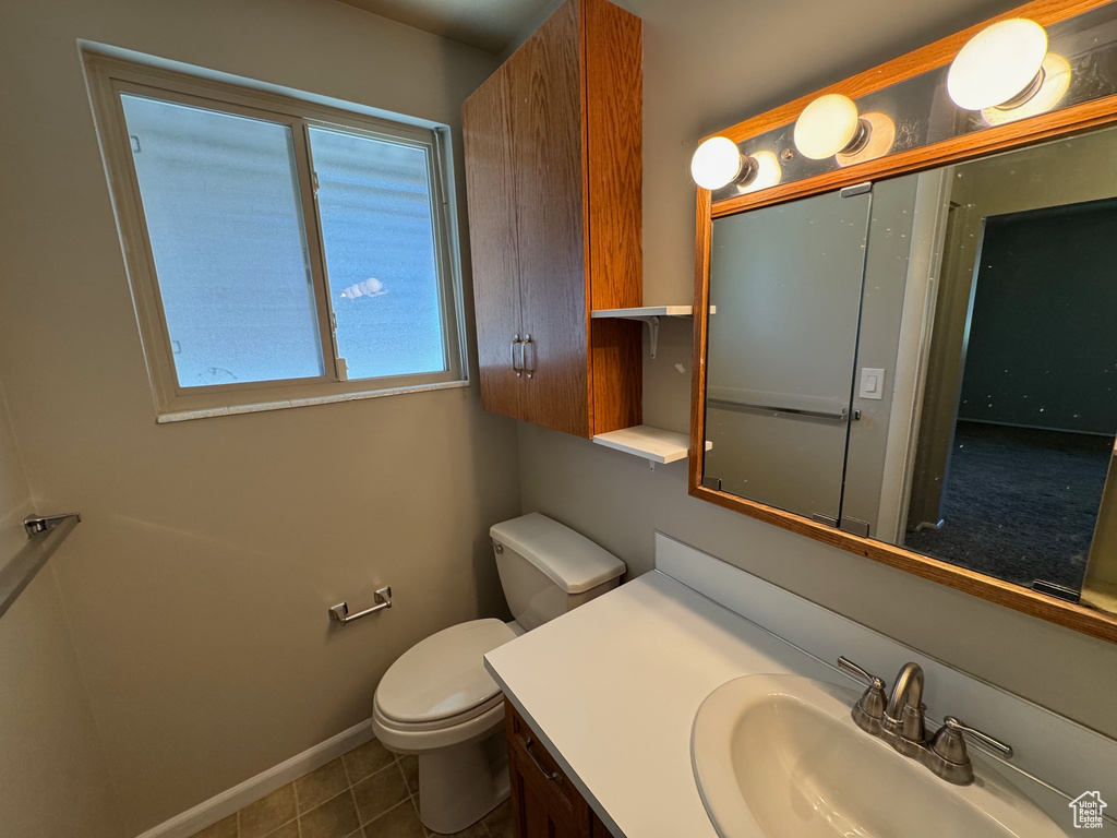 Bathroom with baseboards, tile patterned flooring, vanity, and toilet
