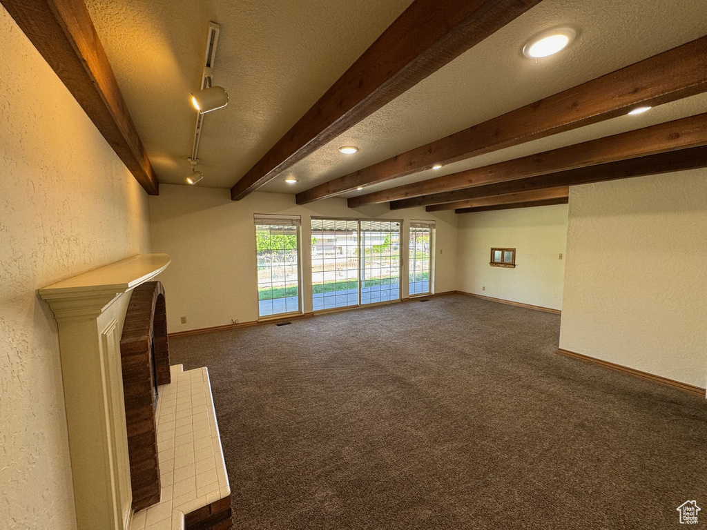 Unfurnished living room with carpet flooring, baseboards, and a textured wall