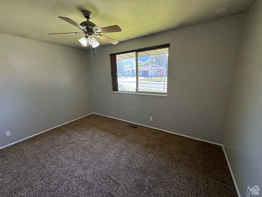 Carpeted empty room featuring baseboards, a ceiling fan, and visible vents