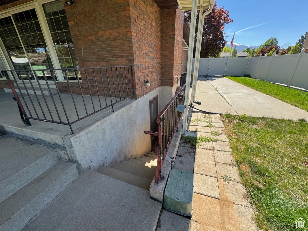 View of home's exterior featuring brick siding, fence, and a porch