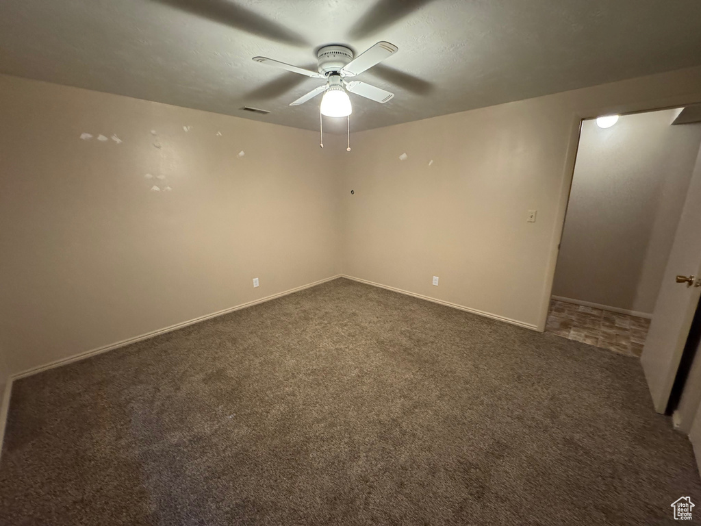 Carpeted empty room featuring visible vents, baseboards, and ceiling fan