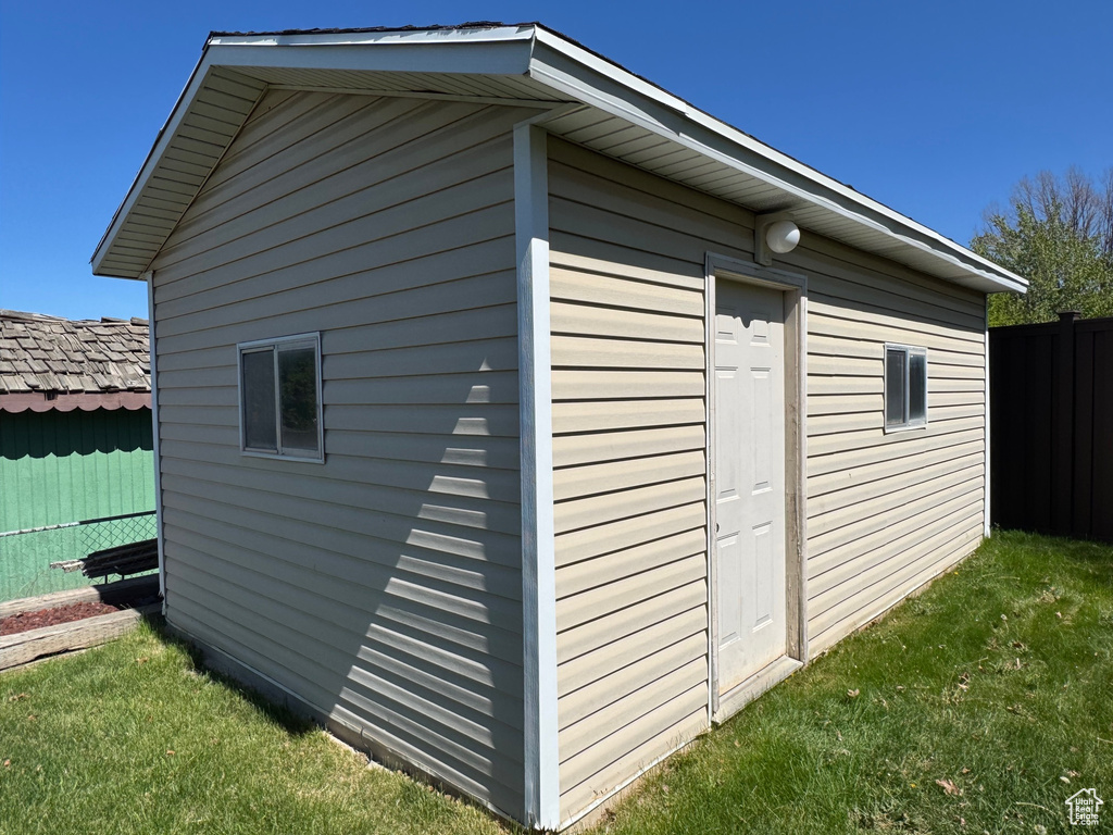 View of outdoor structure featuring an outbuilding and fence