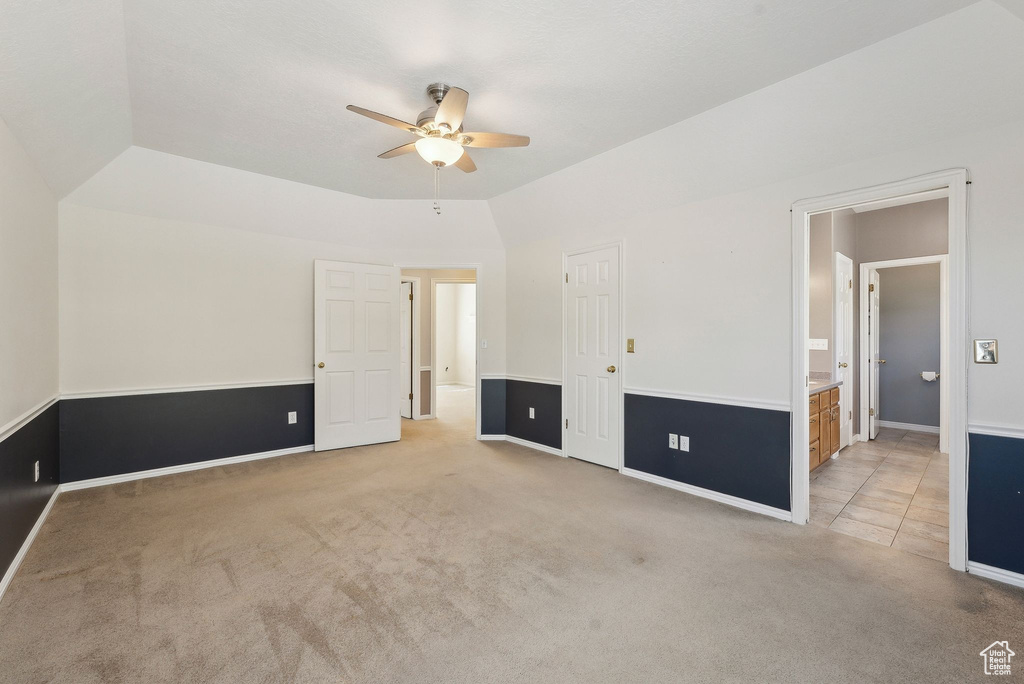 Unfurnished bedroom with light colored carpet, connected bathroom, baseboards, and a ceiling fan