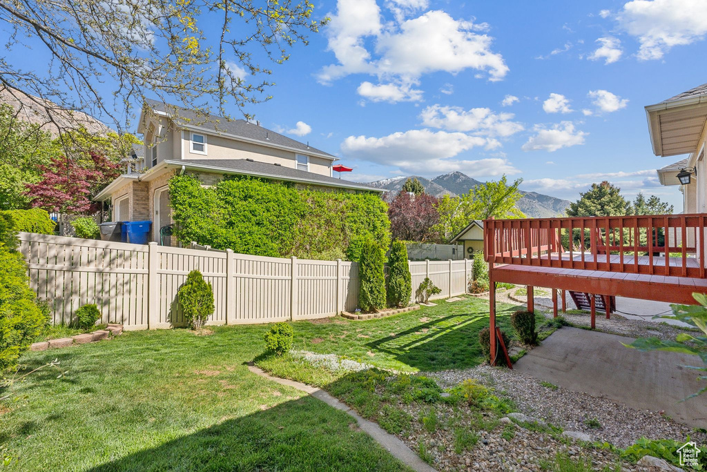 View of yard featuring a deck with mountain view and fence