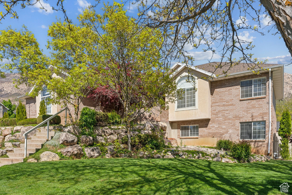 View of front of property with stucco siding, a front lawn, and brick siding