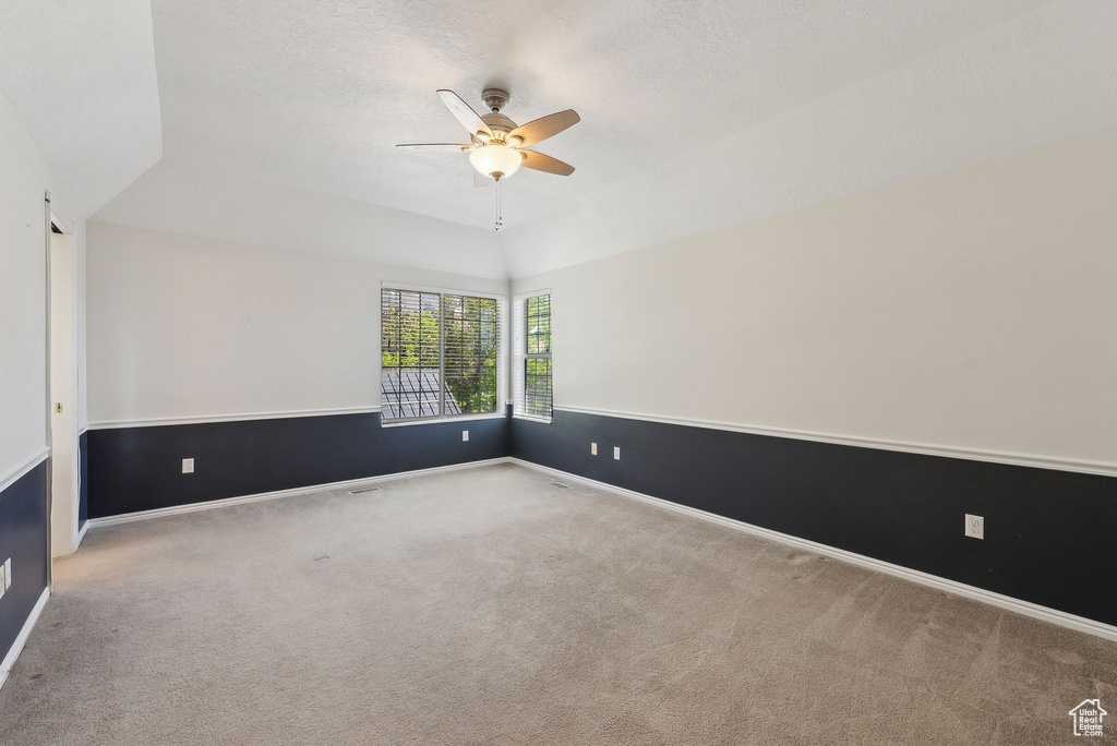 Carpeted spare room with baseboards, lofted ceiling, and ceiling fan