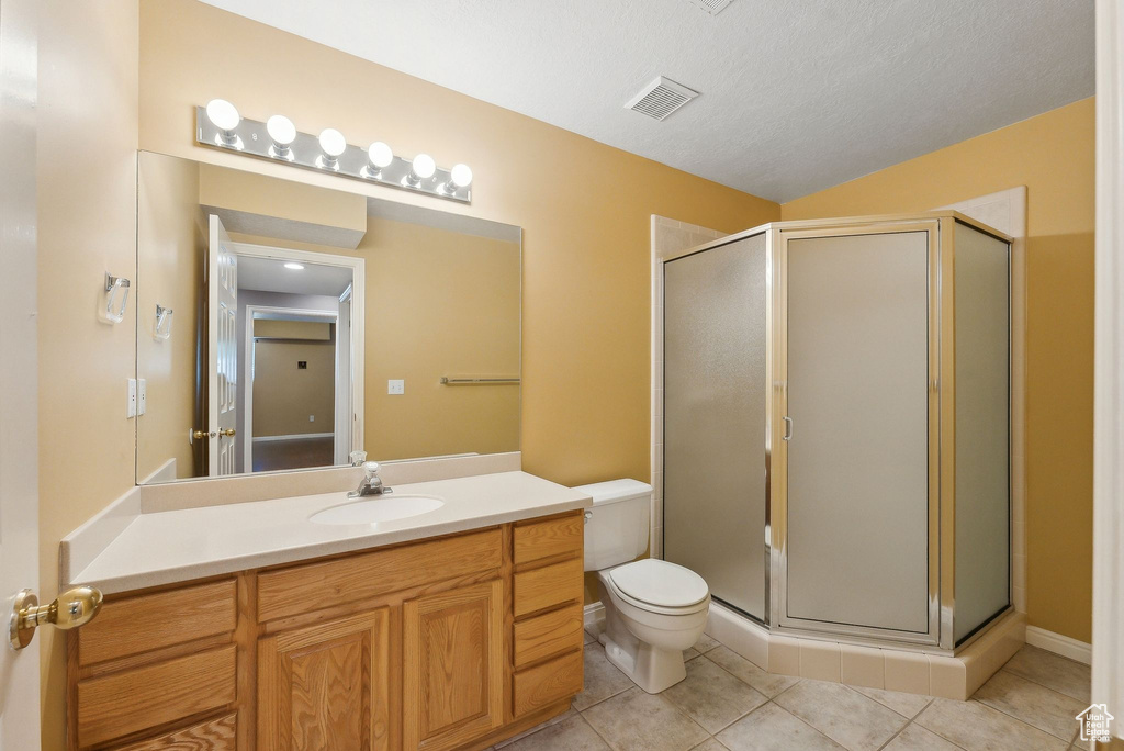 Full bath featuring toilet, tile patterned floors, visible vents, a shower stall, and vanity