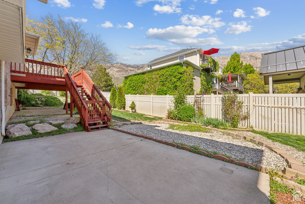 View of patio with a fenced backyard, a deck with mountain view, and stairway