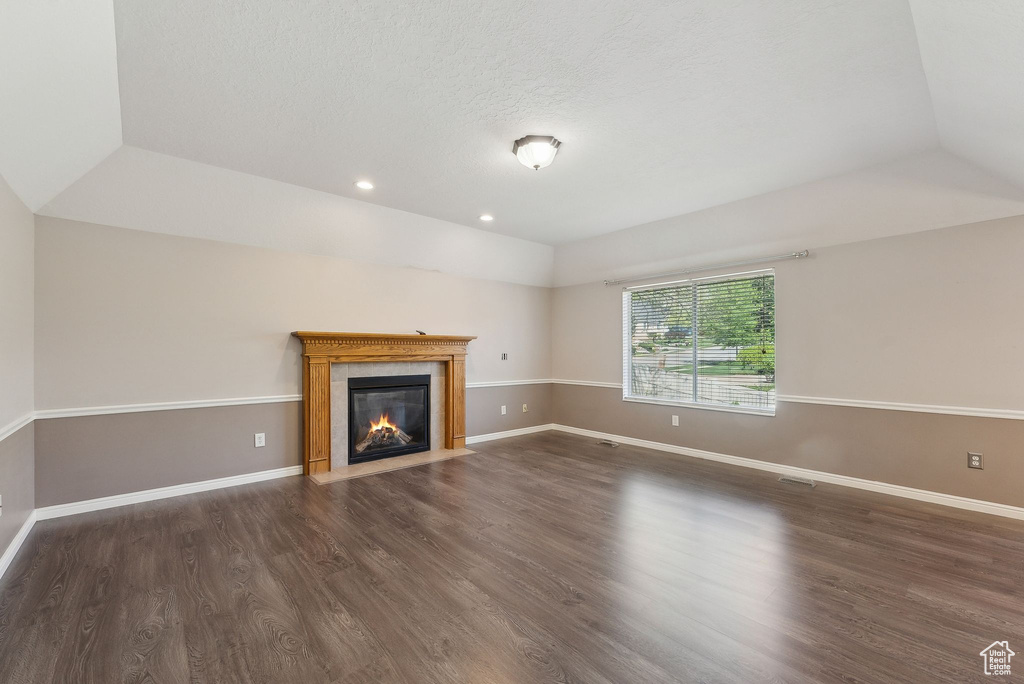 Unfurnished living room featuring dark wood-style flooring, a fireplace, baseboards, and recessed lighting