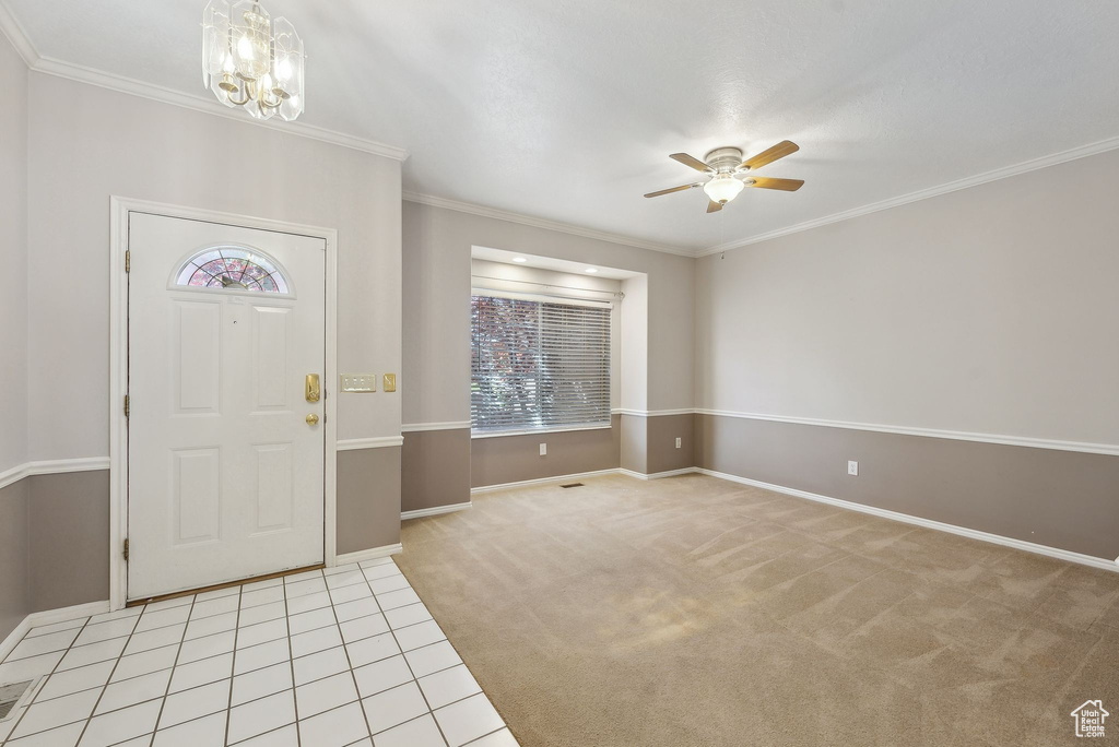 Entrance foyer featuring plenty of natural light, light carpet, baseboards, and ceiling fan with notable chandelier
