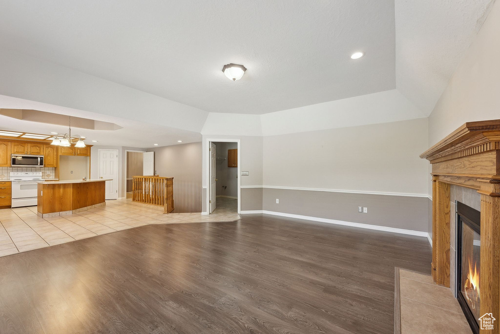 Unfurnished living room featuring baseboards, light wood finished floors, a tiled fireplace, and recessed lighting