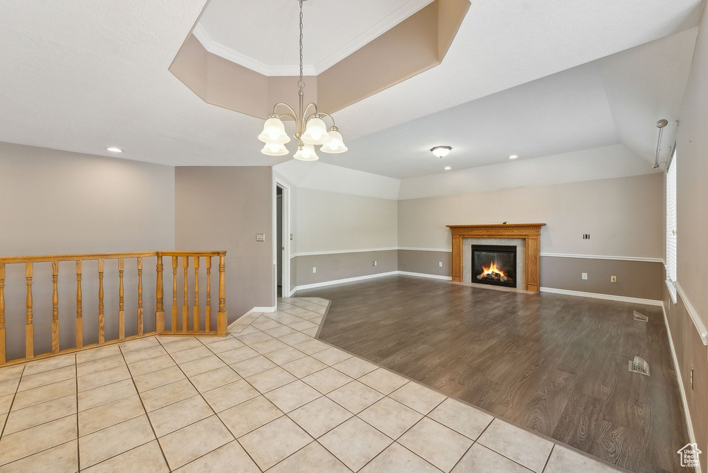 Unfurnished living room with a fireplace, tile patterned flooring, a notable chandelier, and baseboards