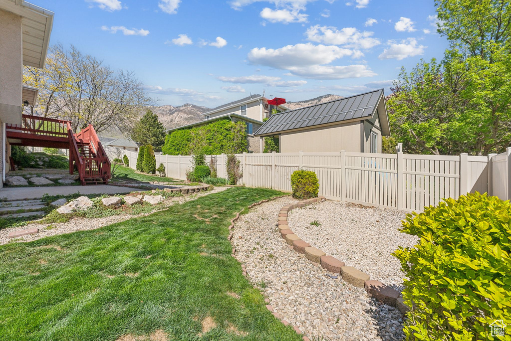 View of yard featuring a deck with mountain view, a fenced backyard, and stairs