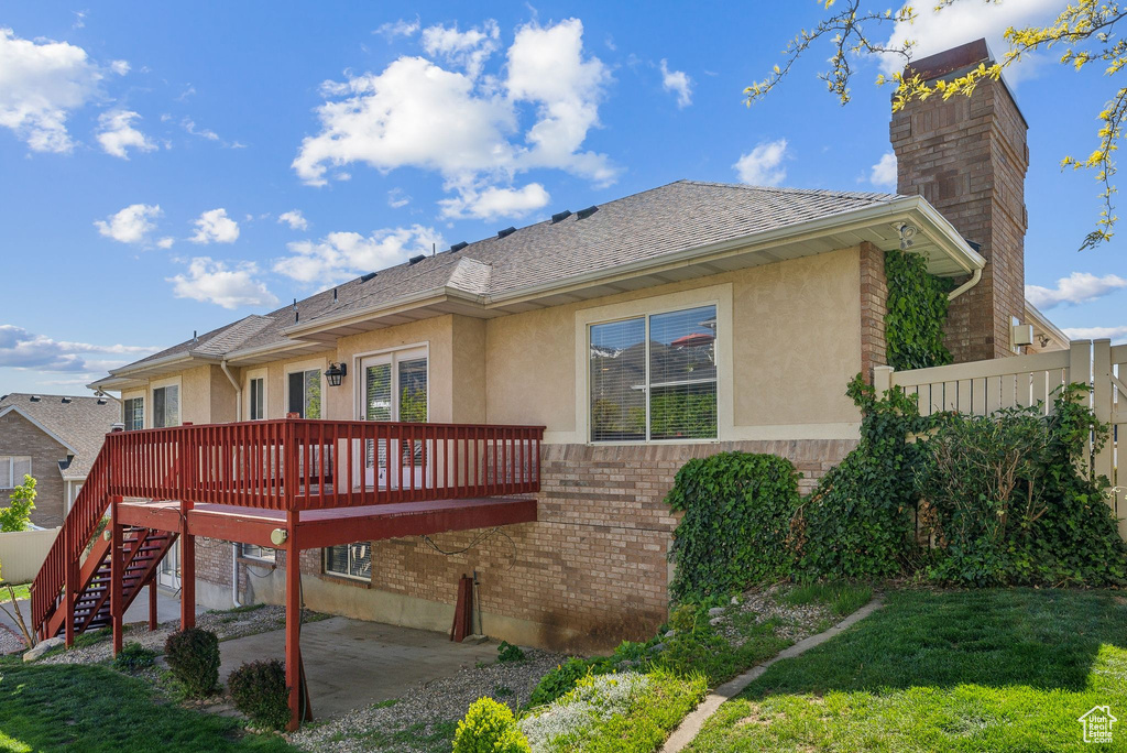 Rear view of property with a wooden deck, a patio, stucco siding, and brick siding