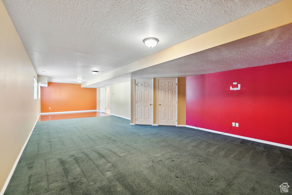 Basement with baseboards, carpet floors, and a textured ceiling