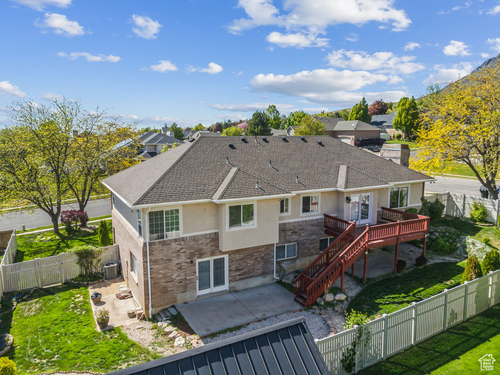 Back of property featuring a patio, stucco siding, a deck, roof with shingles, and a fenced backyard