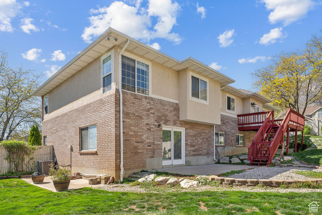 Back of property with a patio, stucco siding, a wooden deck, a yard, and stairs