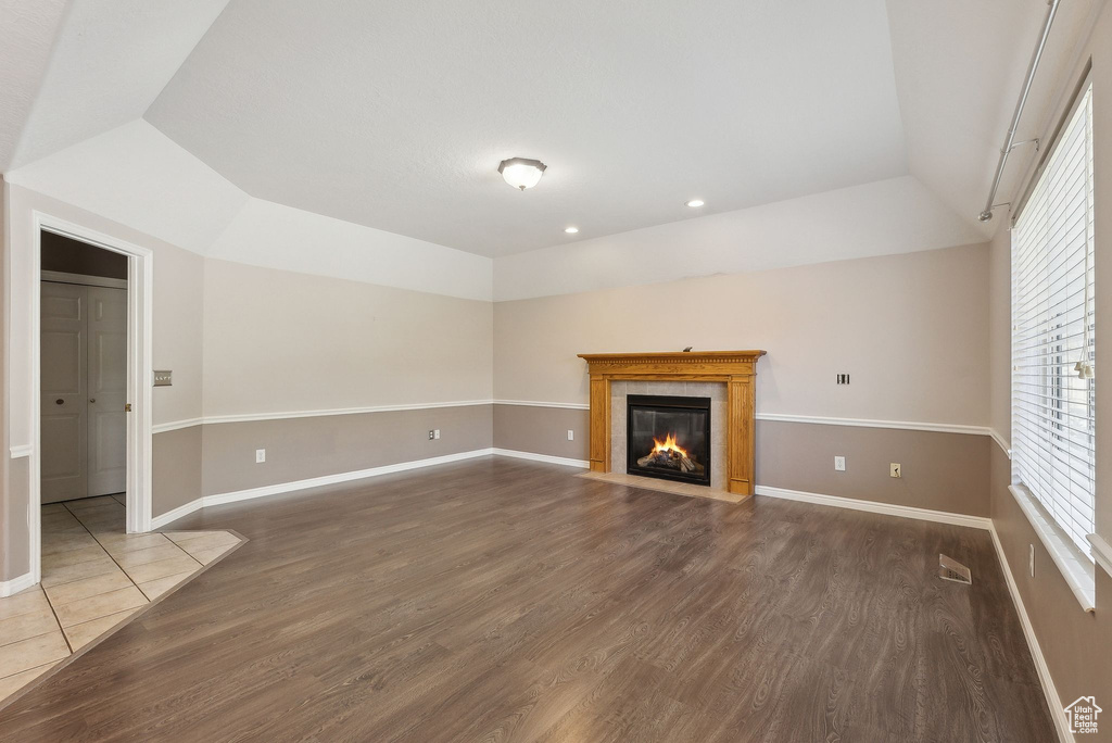 Unfurnished living room with baseboards, dark wood-type flooring, a fireplace, and lofted ceiling