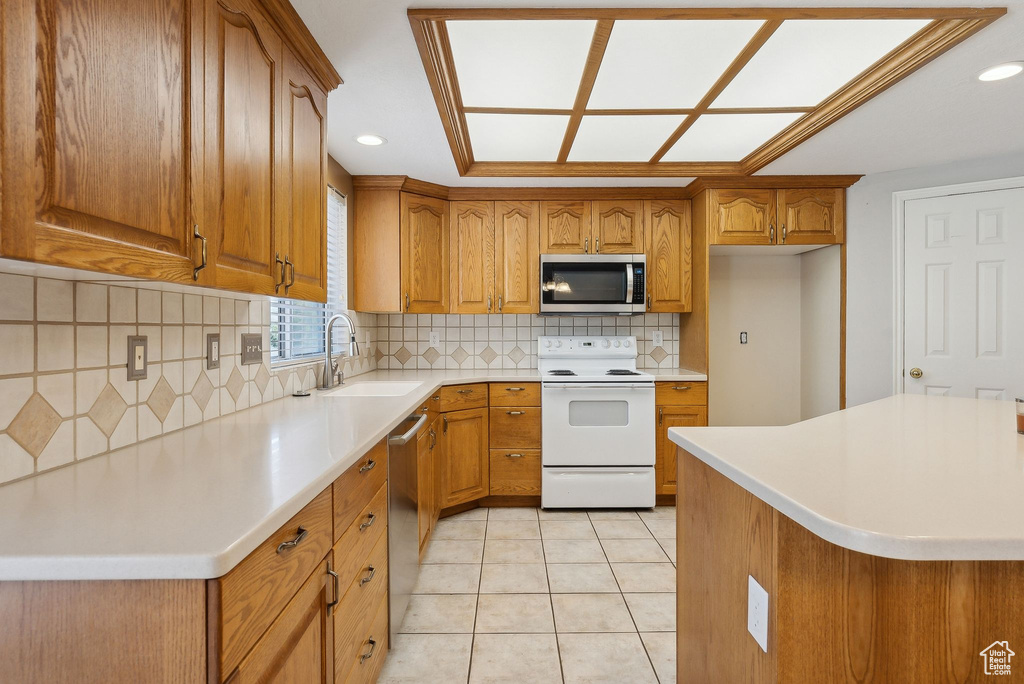 Kitchen with a sink, brown cabinets, light countertops, and appliances with stainless steel finishes