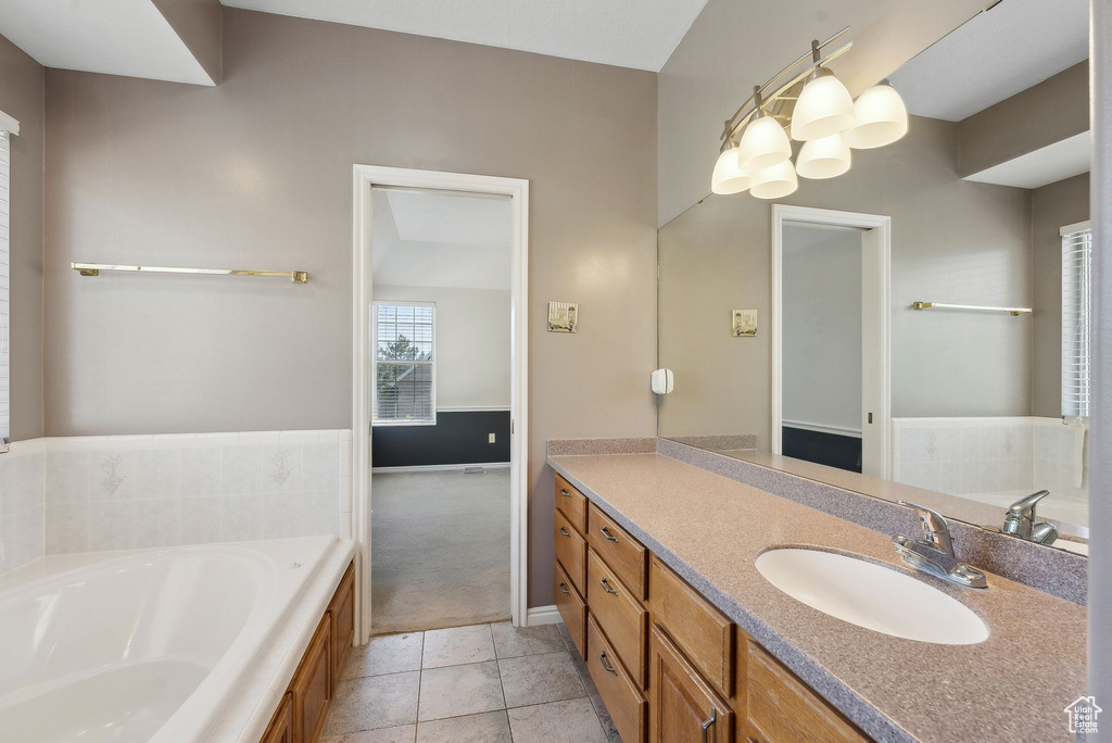 Bathroom featuring vanity, baseboards, a bath, and tile patterned flooring