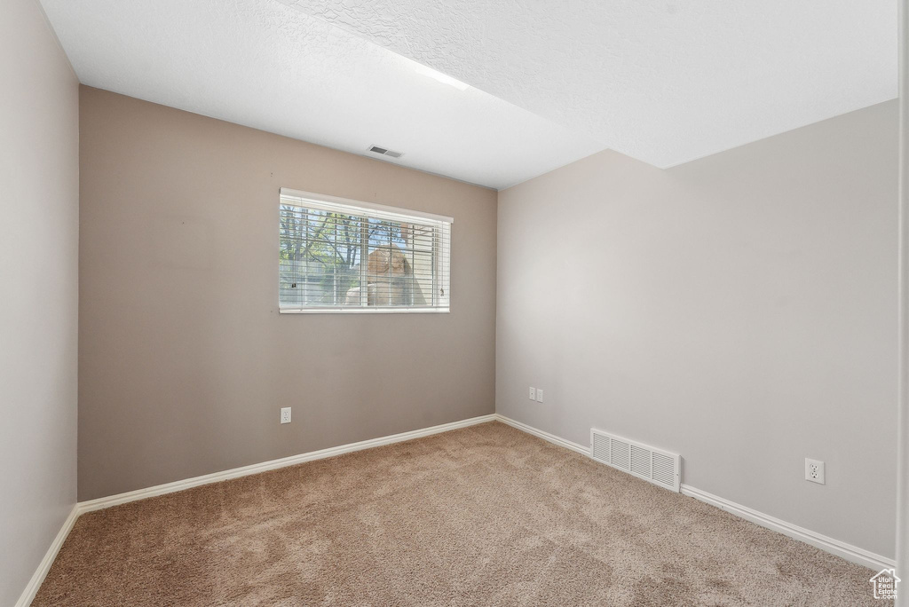Empty room featuring baseboards, visible vents, and carpet floors