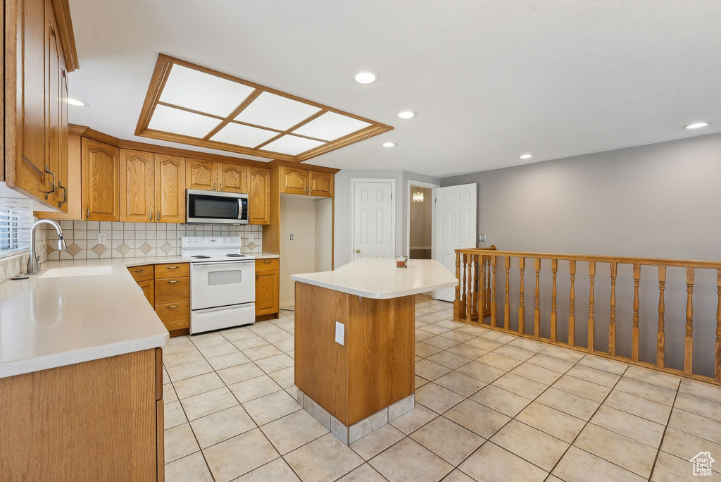 Kitchen featuring recessed lighting, a sink, stainless steel microwave, tasteful backsplash, and electric range