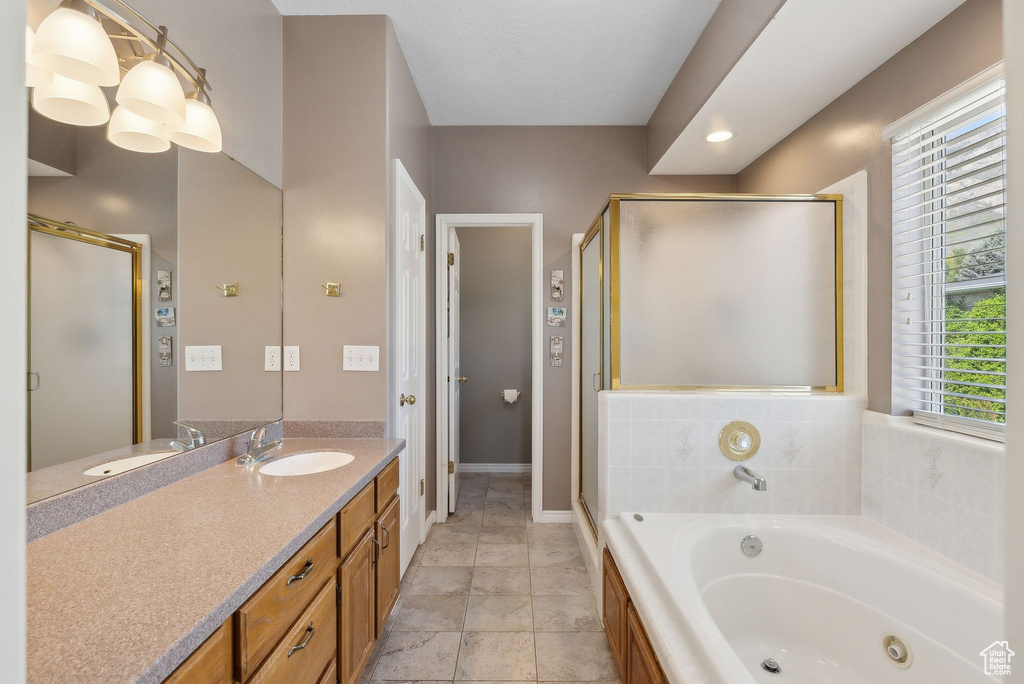 Bathroom with a tub with jets, vanity, a stall shower, and baseboards