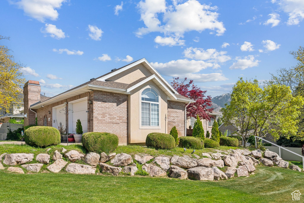 View of home\\\'s exterior featuring an attached garage, brick siding, a chimney, and a lawn