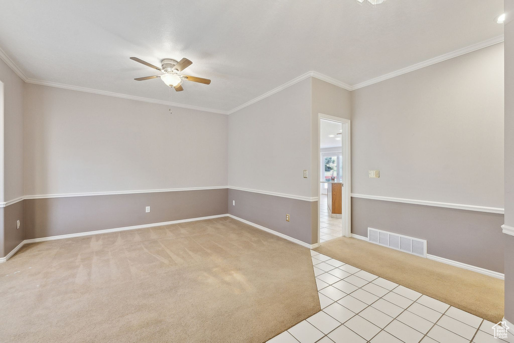 Empty room featuring a ceiling fan, baseboards, visible vents, crown molding, and light carpet