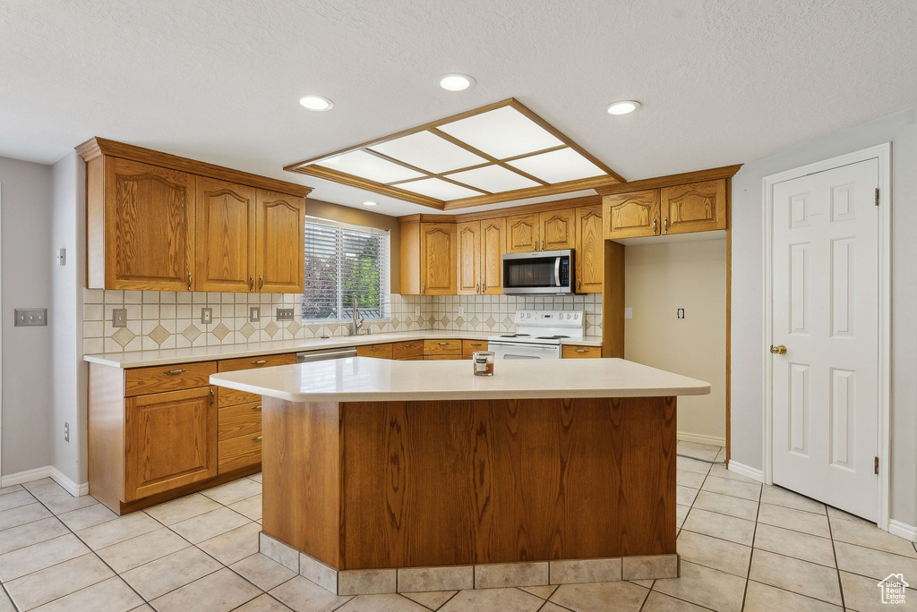 Kitchen with light countertops, a center island, stainless steel microwave, and electric range