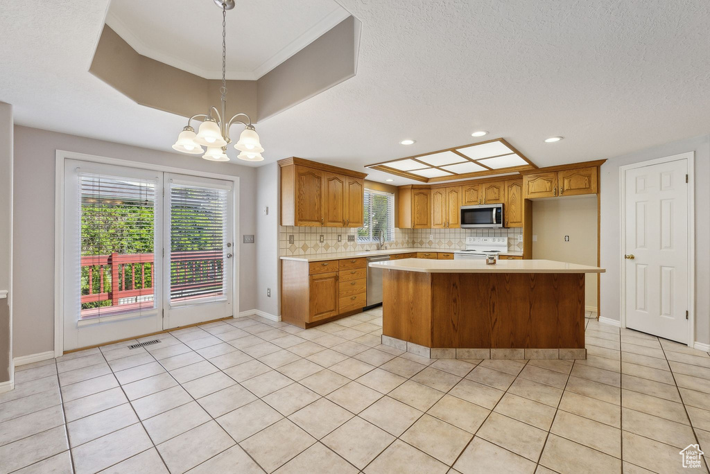 Kitchen with a sink, stainless steel appliances, visible vents, light countertops, and decorative backsplash