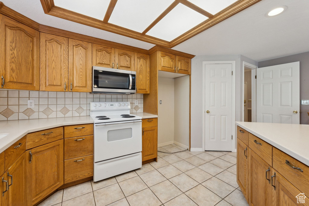 Kitchen featuring brown cabinets, white range with electric stovetop, and stainless steel microwave