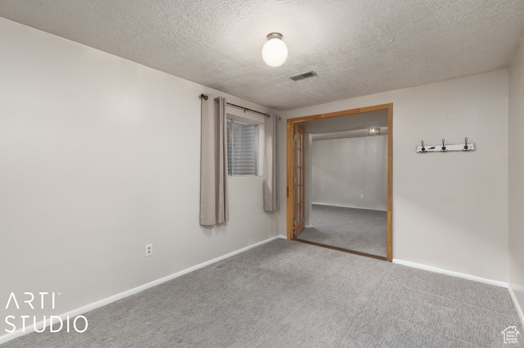 Unfurnished bedroom featuring carpet flooring, a textured ceiling, visible vents, and baseboards