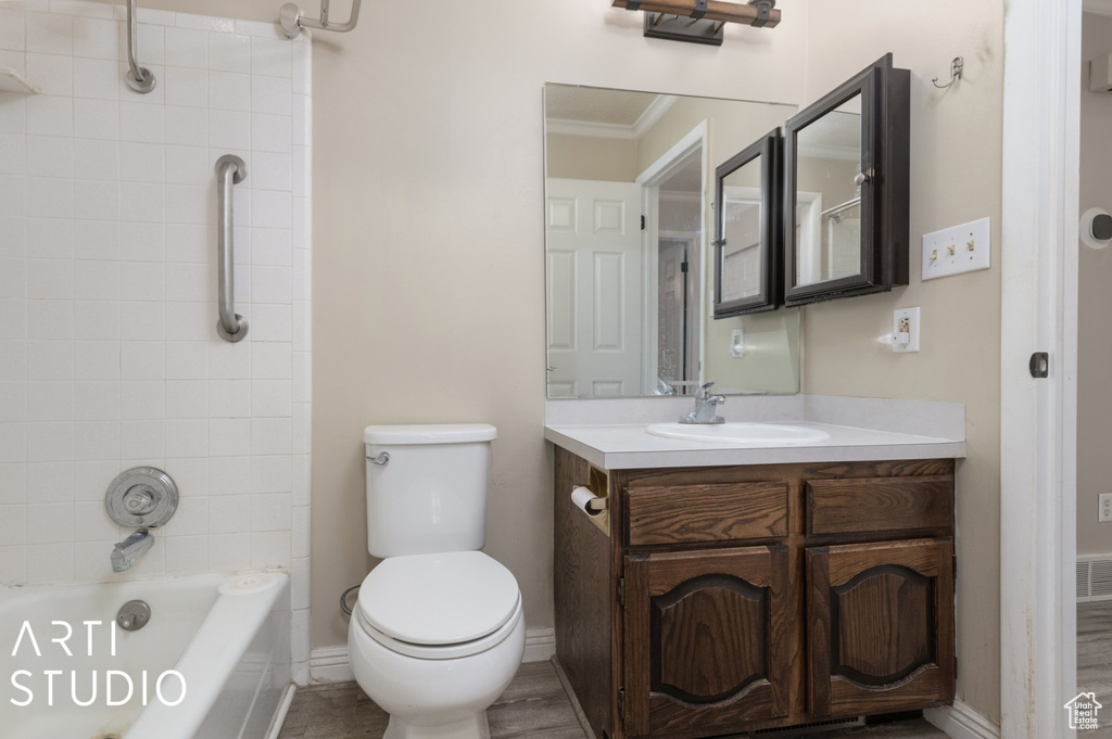 Bathroom with toilet, bathing tub / shower combination, baseboards, vanity, and ornamental molding