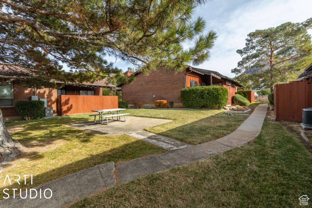 View of yard with central air condition unit, a patio, and fence