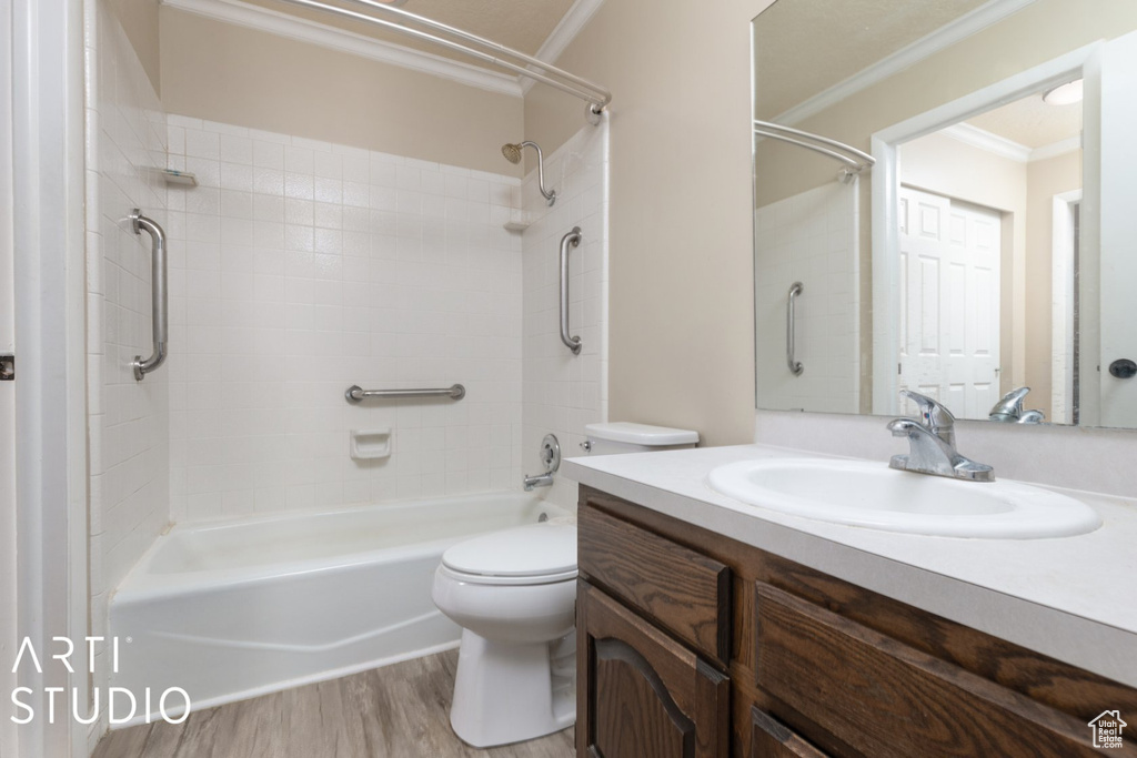 Full bath with toilet, wood finished floors, bathtub / shower combination, vanity, and ornamental molding
