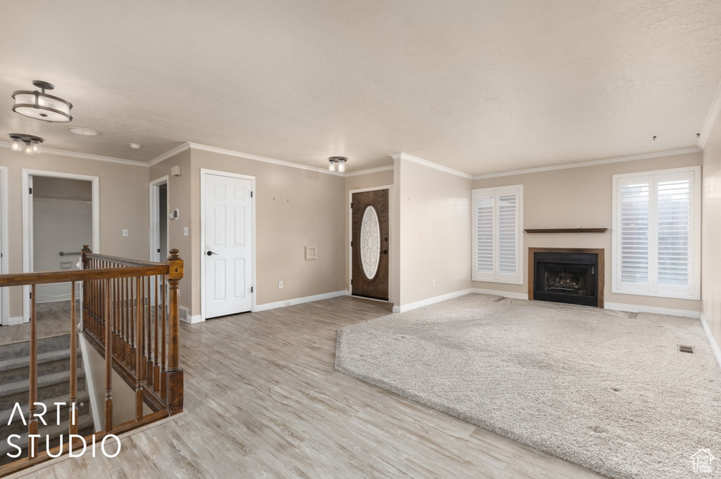Unfurnished living room with ornamental molding, baseboards, a fireplace with flush hearth, and wood finished floors