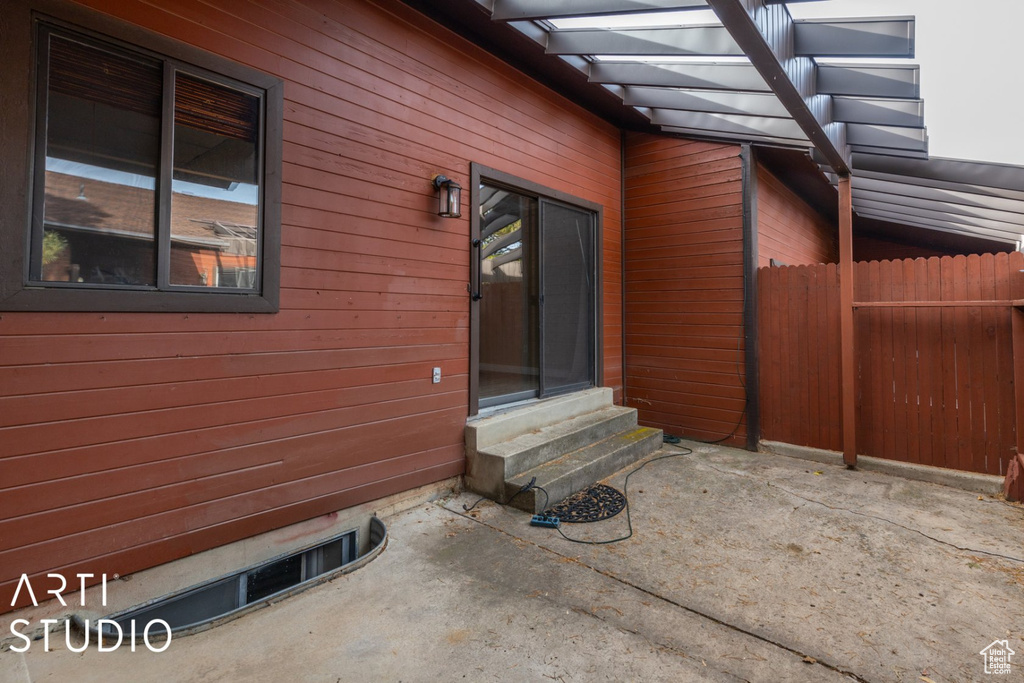 View of side of home featuring entry steps, a patio, and fence