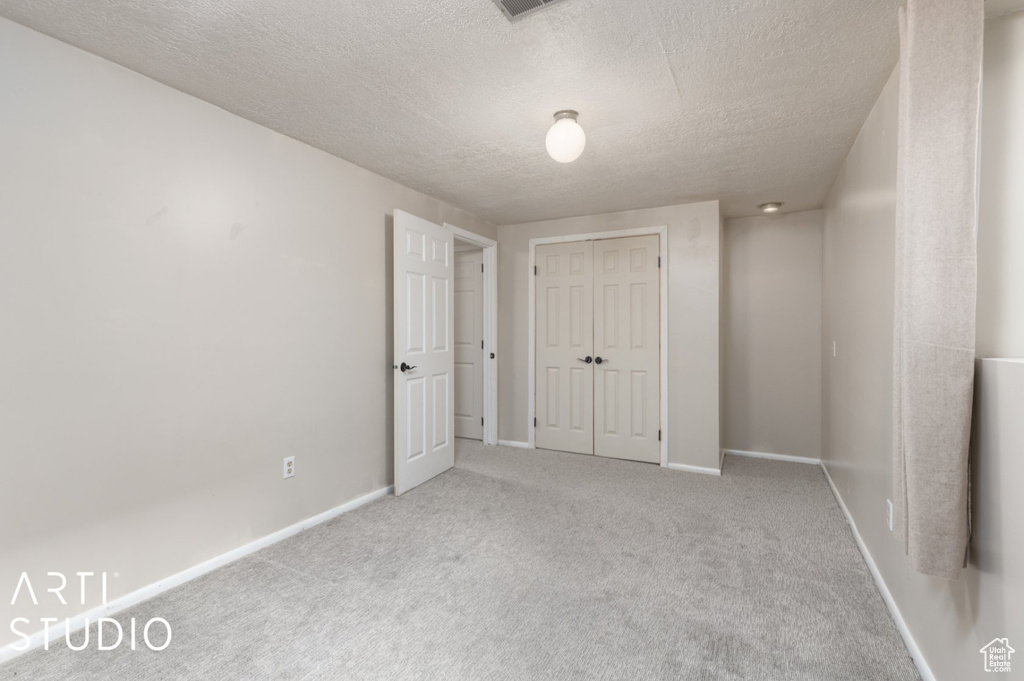 Interior space with a textured ceiling, baseboards, a closet, and carpet floors
