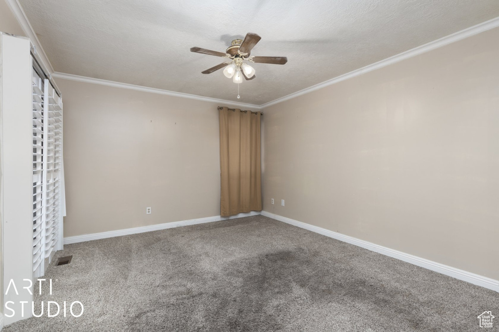 Empty room with ornamental molding, visible vents, ceiling fan, and carpet