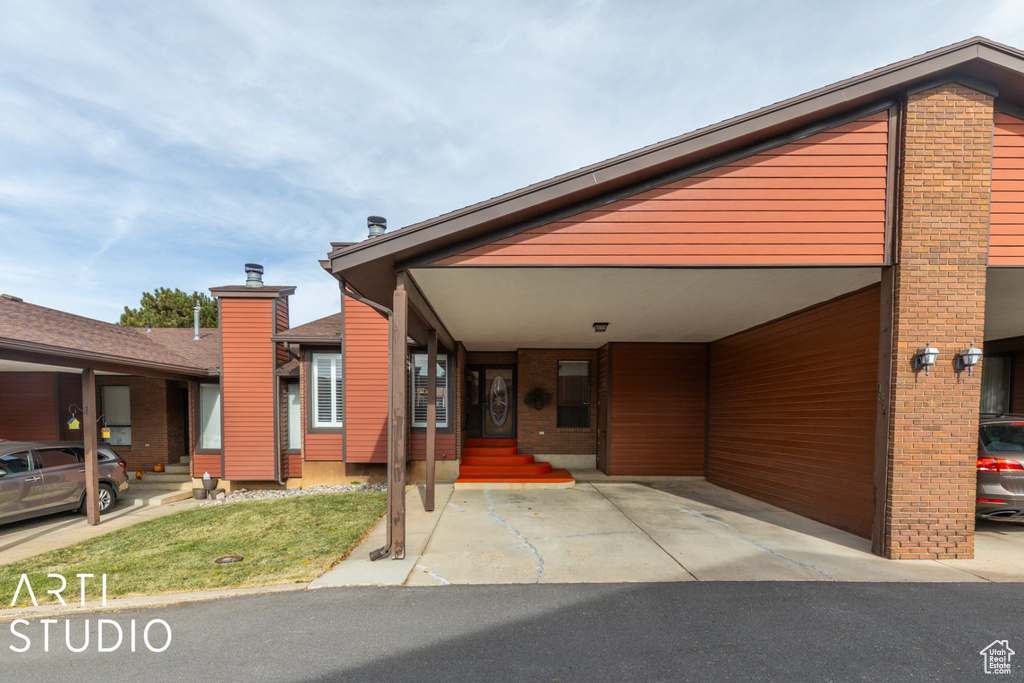 View of front of home featuring brick siding, entry steps, and an attached carport