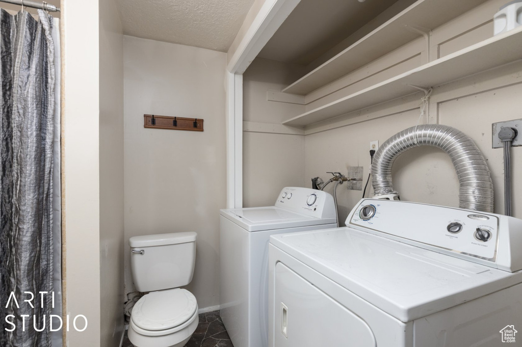 Clothes washing area featuring baseboards, separate washer and dryer, laundry area, and a textured ceiling